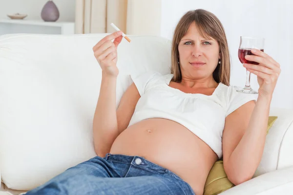 Affascinante donna incinta in possesso di una sigaretta e un bicchiere di rosso w — Foto Stock