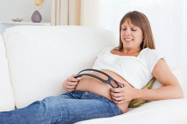 妊娠中の女性とともにヘッドフォン彼女の腹 — ストック写真