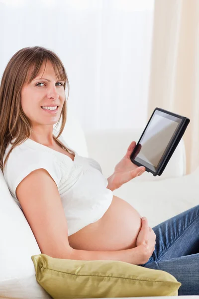 Bella donna incinta che si rilassa con un tablet mentre si siede — Foto Stock