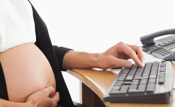 Femme enceinte au téléphone travaillant avec un ordinateur — Photo