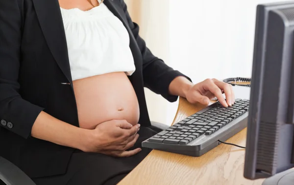 Молодая беременная женщина по телефону работает с компьютером — стоковое фото