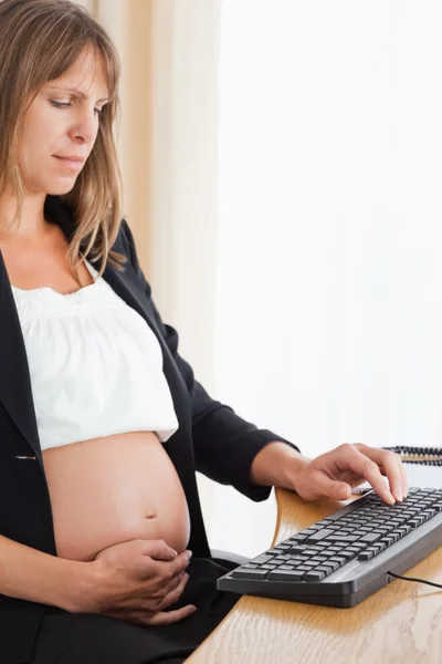Mujer bastante embarazada que trabaja con un ordenador —  Fotos de Stock