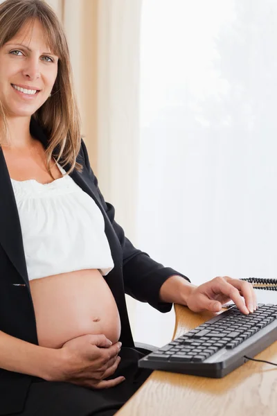Hermosa mujer embarazada que trabaja con un ordenador —  Fotos de Stock