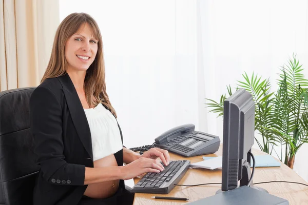 Schöne schwangere Frau, die mit einem Computer arbeitet — Stockfoto