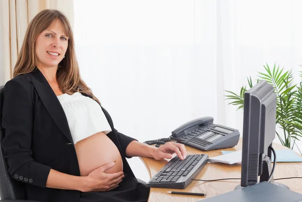 Χαριτωμένο έγκυο γυναίκα που εργάζεται στον ηλεκτονικό υπολογιστή — Φωτογραφία Αρχείου