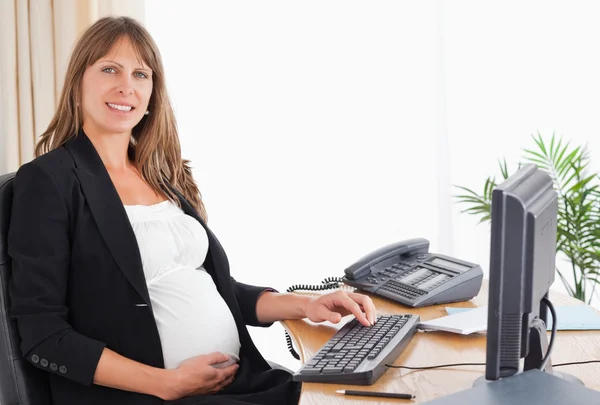Linda mulher grávida trabalhando com um computador — Fotografia de Stock