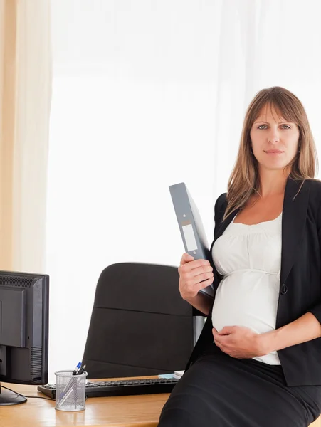 Όμορφη έγκυος γυναίκα, κρατώντας ένα αρχείο ενώ στέκεται — Φωτογραφία Αρχείου