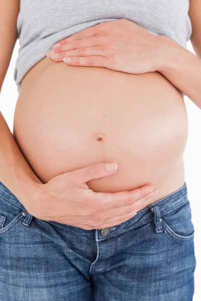 Close-up de uma mulher grávida acariciando a barriga enquanto está de pé — Fotografia de Stock