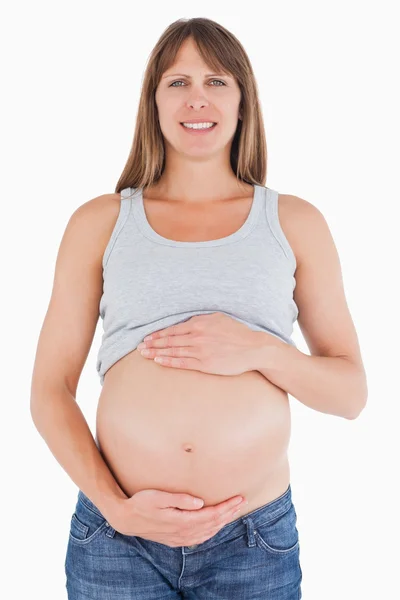 Mujer embarazada hermosa acariciando su vientre mientras está de pie — Foto de Stock