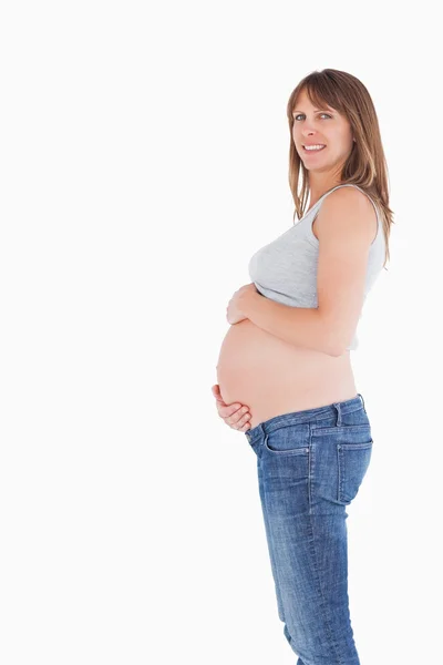 Vista lateral de una mujer embarazada de buen aspecto acariciando su vientre w —  Fotos de Stock