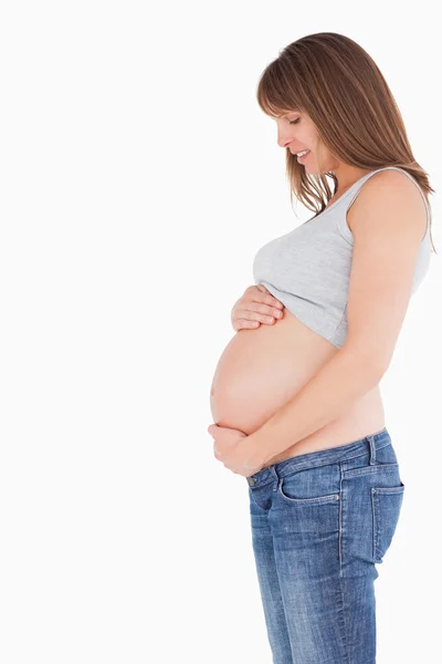 Вид сбоку на привлекательную беременную женщину, ласкающую живот — стоковое фото