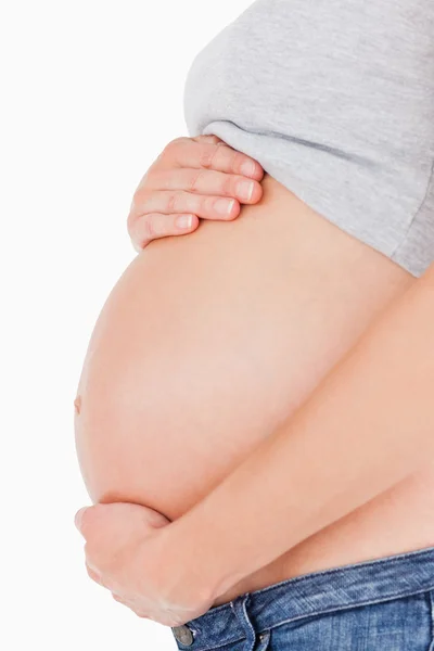 Боковой вид беременной женщины, ласкающей живот стоя — стоковое фото
