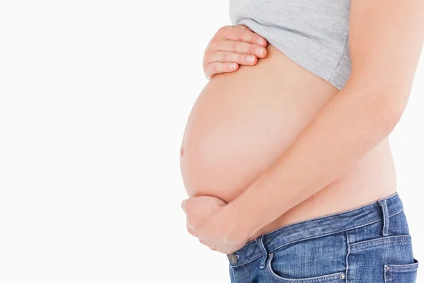 Seitenansicht einer jungen schwangeren Frau, die ihren Bauch streichelt, während — Stockfoto