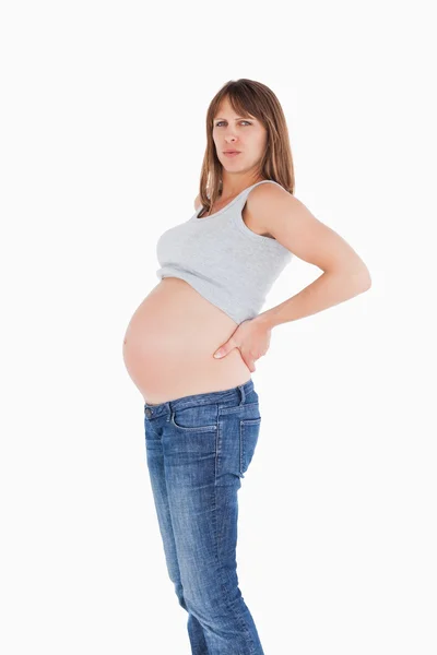 Piękna kobieta w ciąży, trzymając ją z powrotem stojąc — Zdjęcie stockowe