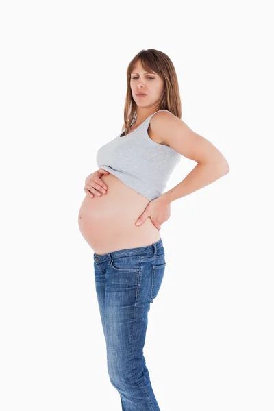 Привлекательная беременная женщина, удерживающая ее, стоя — стоковое фото