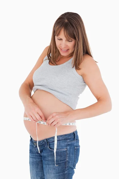 Atrakcyjna kobieta w ciąży pomiaru brzuchu stojąc — Zdjęcie stockowe