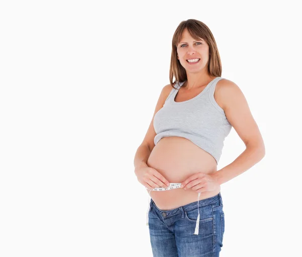 Mulher muito grávida medindo sua barriga em pé — Fotografia de Stock
