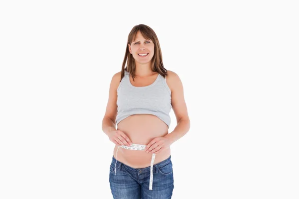 魅力孕妇测量她的腹部站立时 — 图库照片