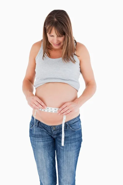 Прекрасна вагітна жінка вимірює живіт, стоячи — стокове фото