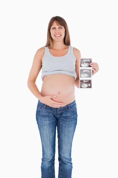 Hermosa mujer embarazada mostrando un ultrasonido mientras está de pie —  Fotos de Stock