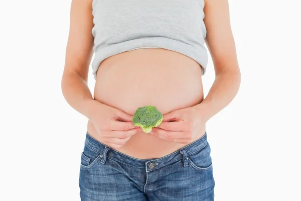 立っているブロッコリーを保持している若い妊娠中の女性 — ストック写真