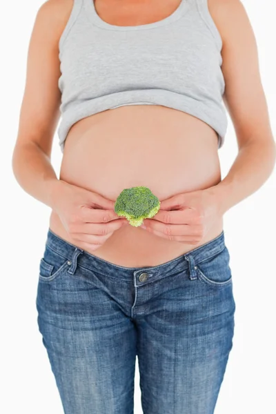 Pregnant woman holding a broccoli while standing — Stok fotoğraf