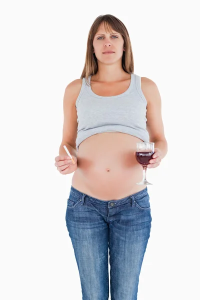 Schöne schwangere Frau hält am Stand ein Glas Rotwein — Stockfoto