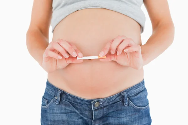 Mujer embarazada sosteniendo un cigarrillo mientras está de pie —  Fotos de Stock