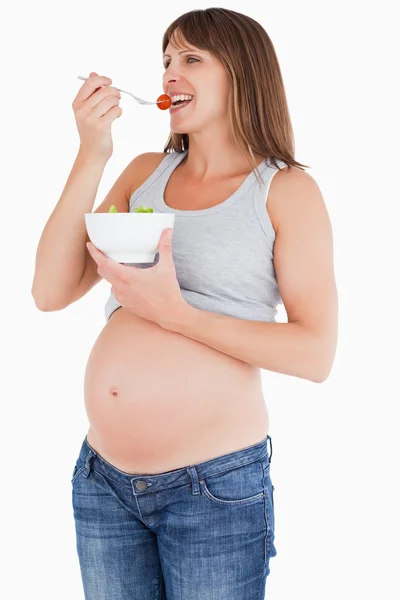Hermosa mujer embarazada comiendo un tomate cereza mientras sostiene un —  Fotos de Stock