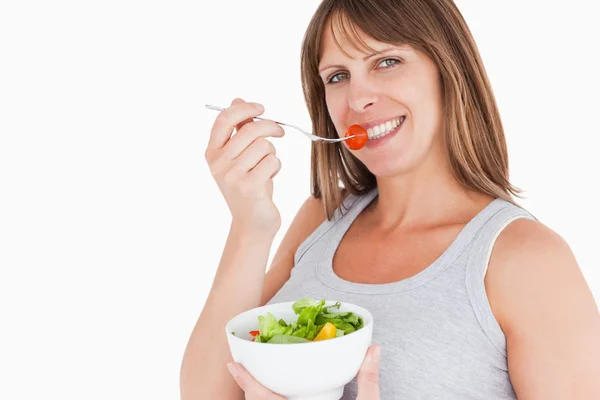 Gut aussehende schwangere Frau isst eine Kirschtomate, während sie — Stockfoto