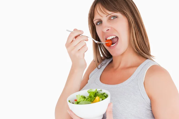 Hübsche schwangere Frau isst eine Kirschtomate, während sie eine Schleife hält — Stockfoto