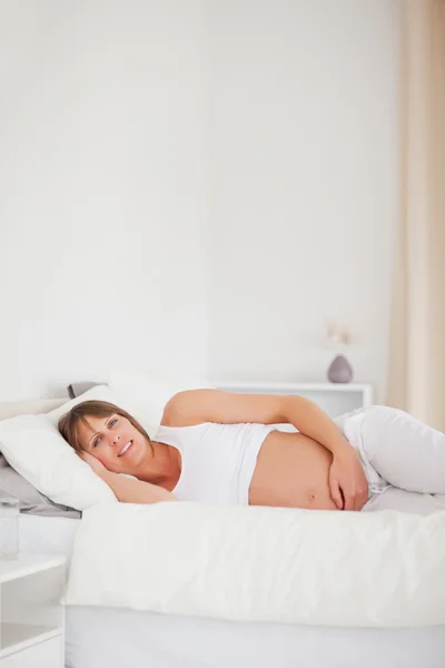 Dobře vypadající těhotná žena relaxaci vleže na posteli — Stock fotografie