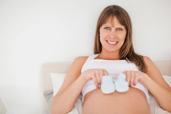 Söta gravida kvinna som spelar med lite strumpor liggande på en b — Stockfoto