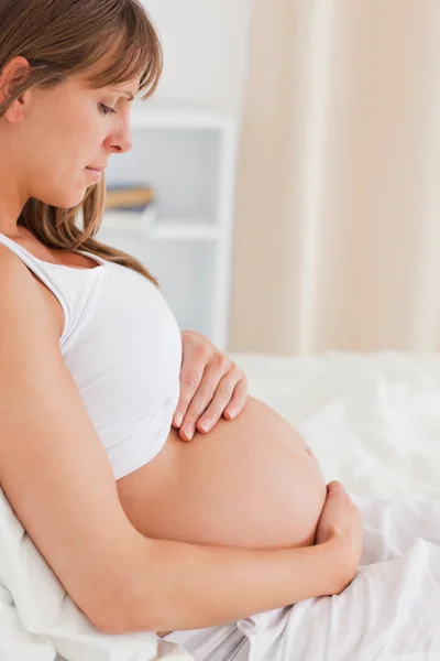 Portret van een charmante zwangere vrouw liggen op een bed — Stockfoto
