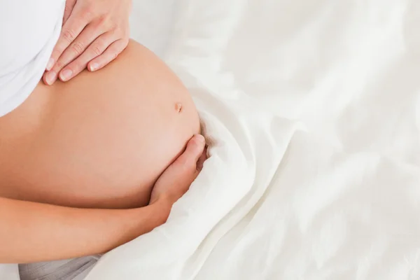 Nahaufnahme einer jungen schwangeren Frau, die auf einem Bett liegt — Stockfoto