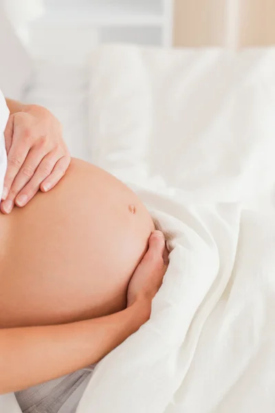 Крупный план молодой беременной женщины, лежащей на кровати — стоковое фото