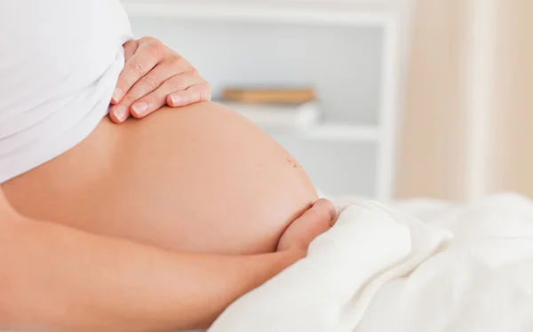 Close-up de uma mulher grávida deitada em uma cama — Fotografia de Stock