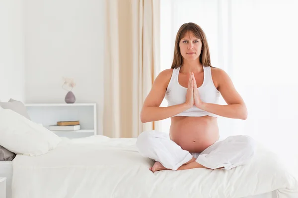 Hermosa mujer embarazada haciendo yoga en una cama —  Fotos de Stock