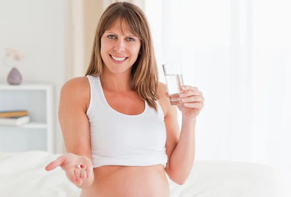 Porträt einer attraktiven schwangeren Frau, die eine Pille nimmt, während sie — Stockfoto