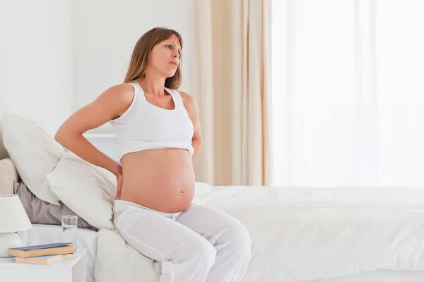 Привлекательная беременная женщина с болью в спине, сидя на — стоковое фото