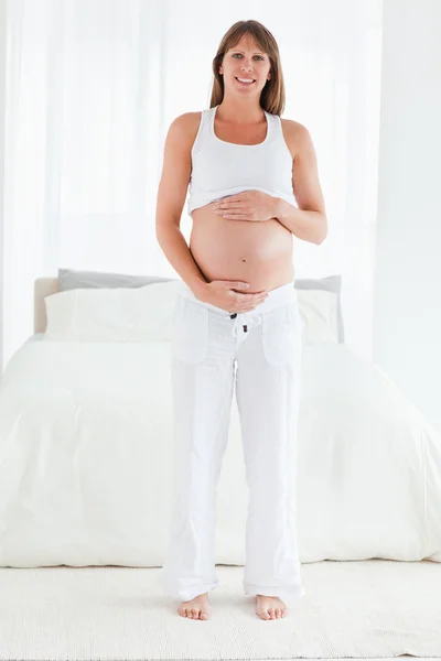 Bella femmina incinta in posa mentre in piedi — Foto Stock