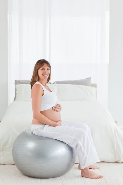 Красивая беременная женщина ласкает живот, сидя на — стоковое фото