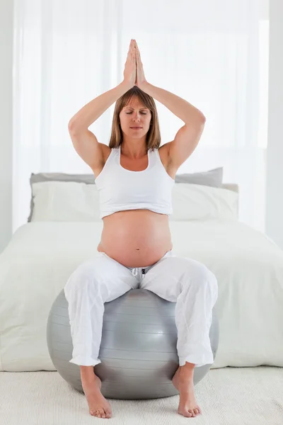 Bastante embarazada hembra haciendo ejercicios de relajación mientras está sentado — Foto de Stock