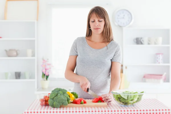 Приваблива вагітна жінка позує під час приготування овочів — стокове фото