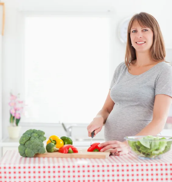 Dobře vypadající těhotná žena pózuje při vaření zeleniny — Stock fotografie