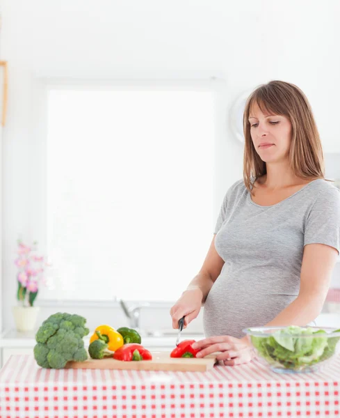 Velmi těhotná žena pózuje při vaření zeleniny — Stock fotografie