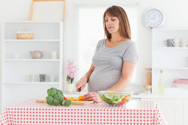 Linda mulher grávida posando enquanto cozinha legumes — Fotografia de Stock