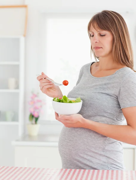 Dobře vypadající těhotná žena jíst cherry rajčátek a standin — Stock fotografie