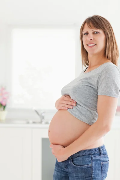 Piękna kobieta w ciąży pozowanie podczas pieszczot jej brzuch — Zdjęcie stockowe