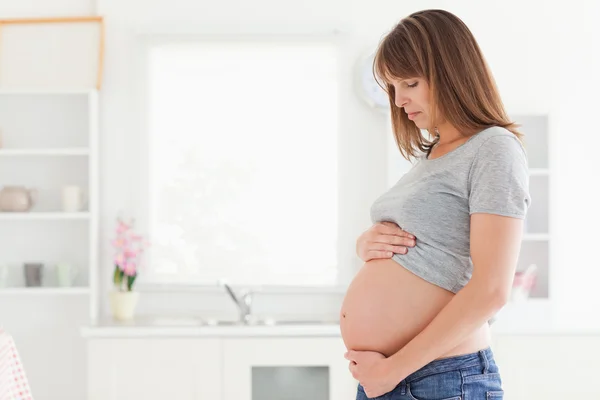 Attraente donna incinta posa mentre accarezza la pancia — Foto Stock